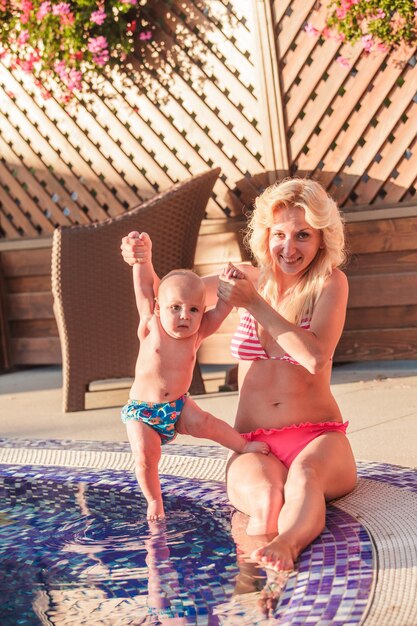 Pretty young mom with baby at the swimming pool