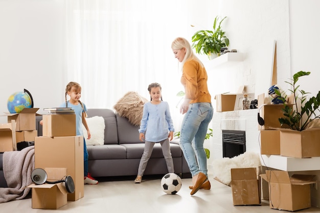 Photo pretty young mother and her cute little daughter having fun in new apartment and unpacking moving boxes