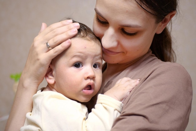 Pretty young mother holding her newborn baby boy close up