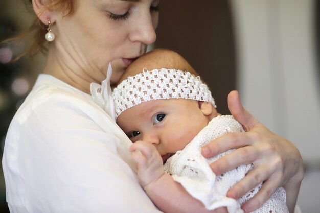 Pretty young mother holding a newborn daughter in her arms