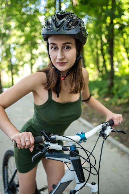 Pretty young slim woman on a bicycle rest after activity in the forest Vacation in summer time Outdoor lifestyle