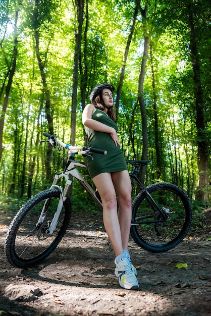 Pretty young slim woman on a bicycle rest after activity in the forest