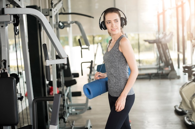 La donna abbastanza giovane di sport è allenamento con la stuoia in palestra, stile di vita sano