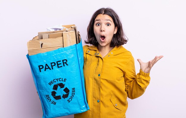 Pretty young woman amazed, shocked and astonished with an unbelievable surprise. paper recycle concept