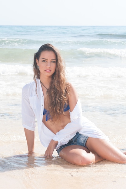 Photo pretty young woman on the beach near the sea in summer or spring