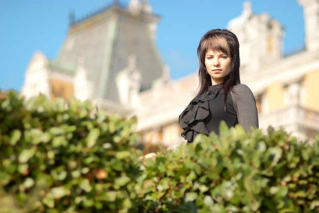 Bella giovane donna in abito nero davanti al castello di lusso