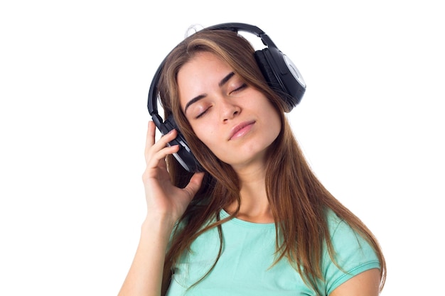 Pretty  young woman in blue Tshirt listening to the music in black headphones with closed eyes