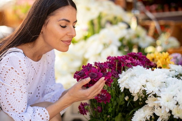 Piuttosto giovane donna che compra fiori al mercato dei fiori