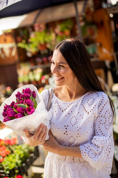 Pretty young woman buying flowers at the flower market