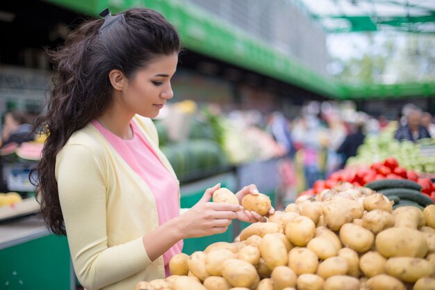 Pretty young woman buying vegetables on the market