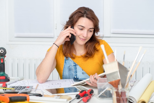 Pretty young woman doing DIY talking on phone