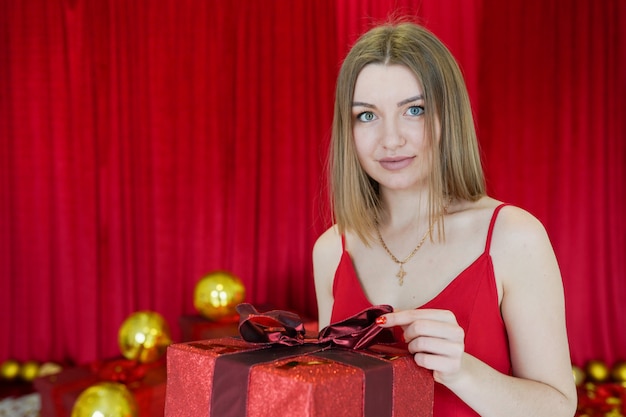 Pretty young woman dressed in red dress with big present