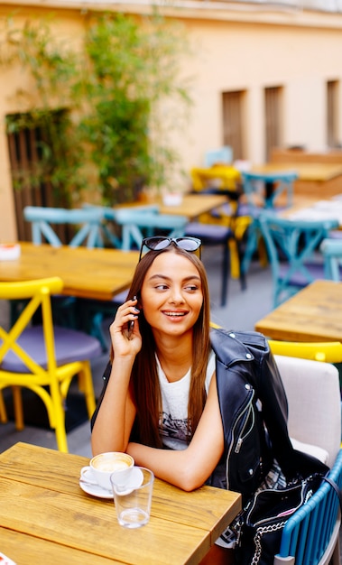 Pretty young woman drinking coffee in cafe on a sunny day