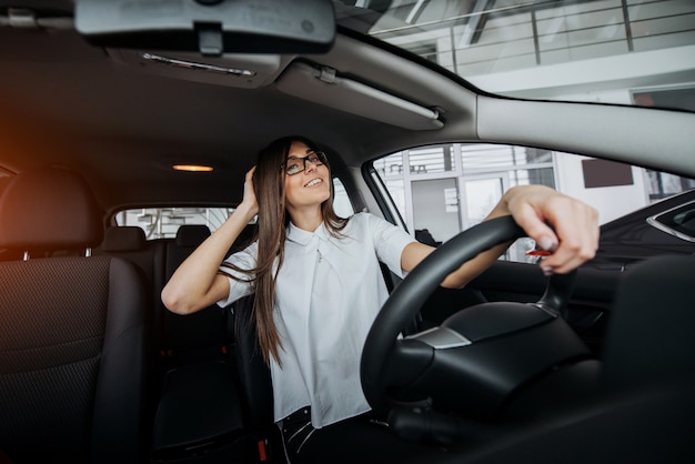 Pretty young woman driving new car.