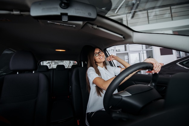 Pretty young woman driving new car.