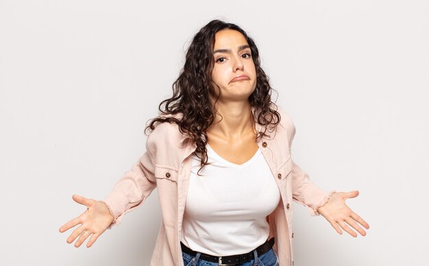 Pretty young woman feeling clueless and confused, having no idea, absolutely puzzled with a dumb or foolish look