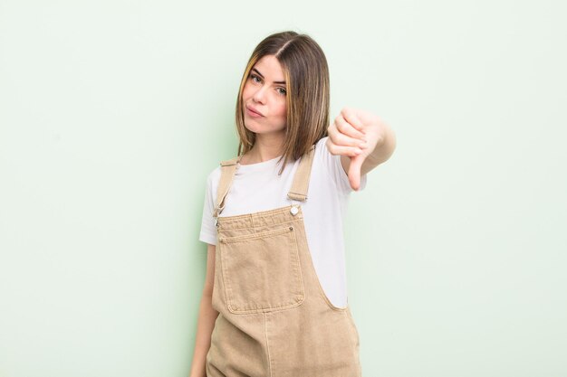 pretty young woman feeling cross, angry, annoyed, disappointed or displeased, showing thumbs down with a serious look