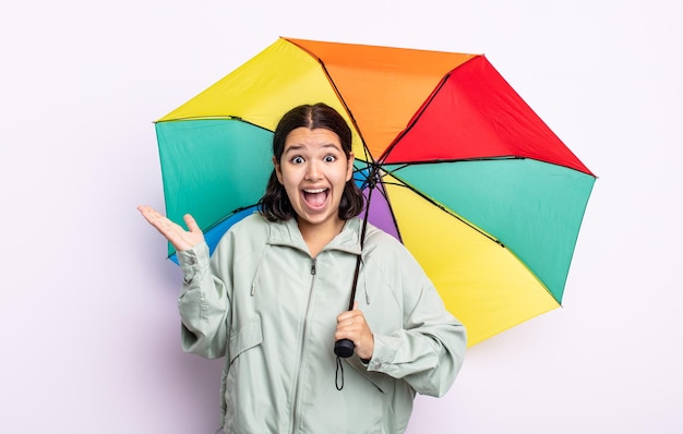 信じられないほどの雨と傘のコンセプトに幸せと驚きを感じているかなり若い女性