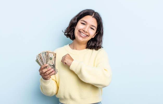 Pretty young woman feeling happy and facing a challenge or celebrating. dollar banknotes concept