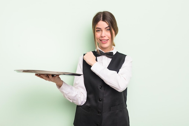 pretty young woman feeling happy and facing a challenge or celebrating. waiter with a tray concept