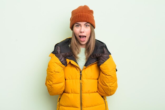 Pretty young woman feeling happy and pointing to self with an excited cold weather concept