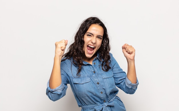 Pretty young woman feeling happy, positive and successful, celebrating victory, achievements or good luck