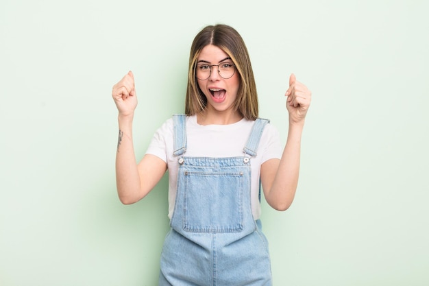 Pretty young woman feeling happy surprised and proud shouting and celebrating success with a big smile