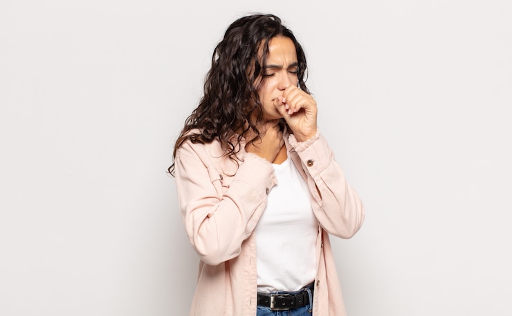 Photo pretty young woman feeling ill with a sore throat and flu symptoms, coughing with mouth covered