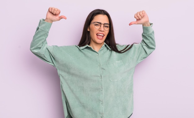 Pretty young woman feeling proud, arrogant and confident, looking satisfied and successful, pointing to self