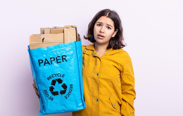 Pretty young woman feeling puzzled and confused. paper recycle concept