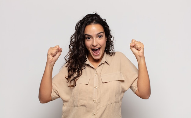 Pretty young woman feeling shocked, excited and happy, laughing and celebrating success, saying wow!