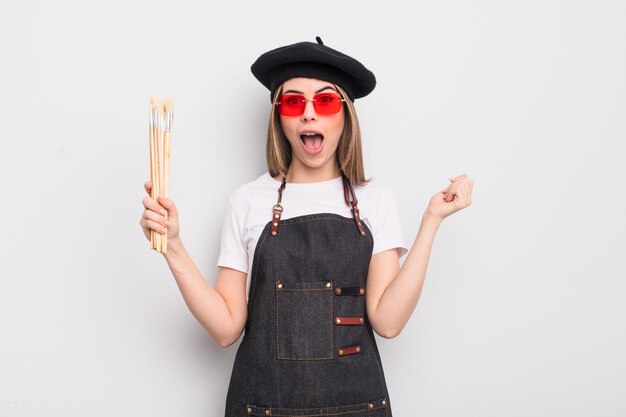 Pretty young woman feeling shocked,laughing and celebrating success. artist with brushes