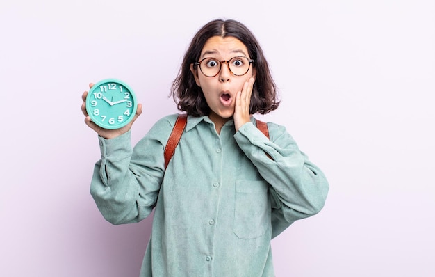 Pretty young woman feeling shocked and scared. alarm clock concept