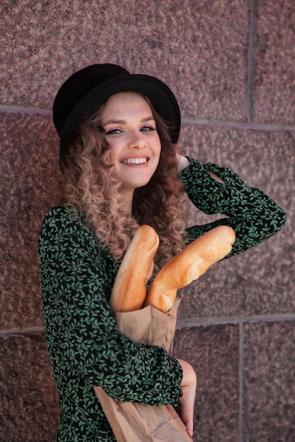 Pretty young woman in French style with baguettes in hands