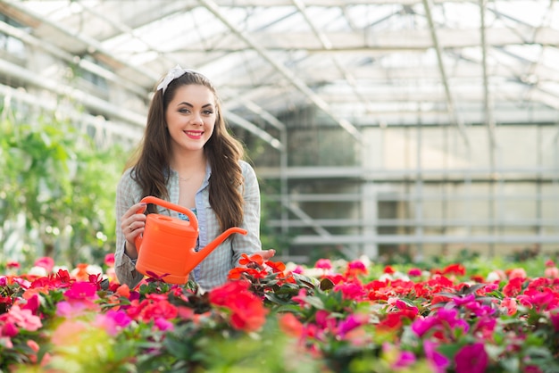 Pretty young woman gardener in the greenhouse among the flowers