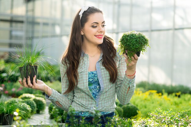 Pretty young woman gardener in the greenhouse among the flowers