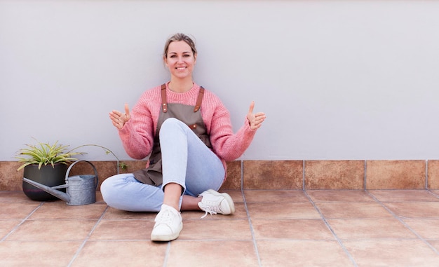 Photo pretty young woman gardering and sitting on the floor outdoors