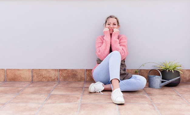 Pretty young woman gardering and sitting on the floor outdoors