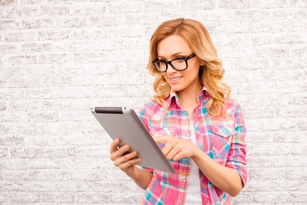 Pretty young woman in glasses touching screen of tablet