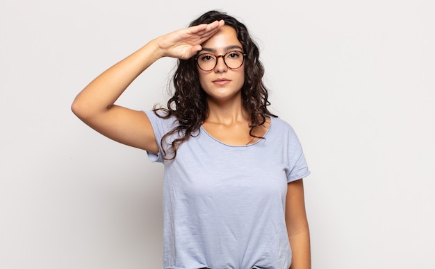 Pretty young woman greeting with a military salute in an act of honor and patriotism, showing respect