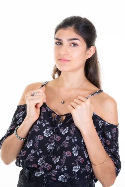 Pretty young woman hair tied with hands on the straps of her top portrait with dark hair brown on white background