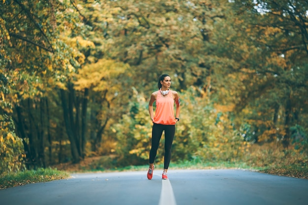 Pretty young woman have a break during training in the autumn forest