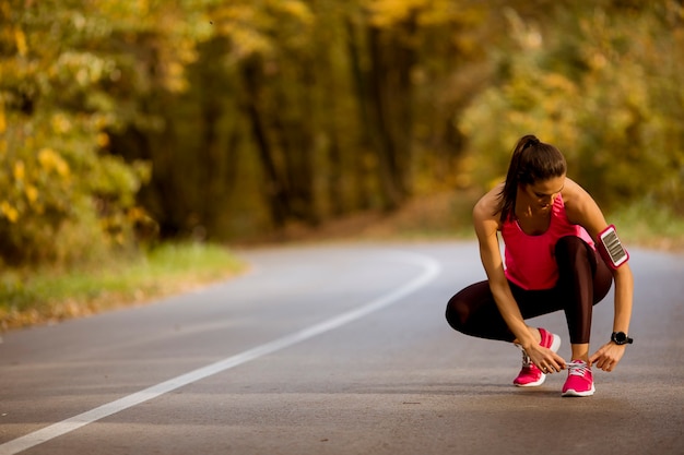 Pretty young woman have a break during training in the autumn forest