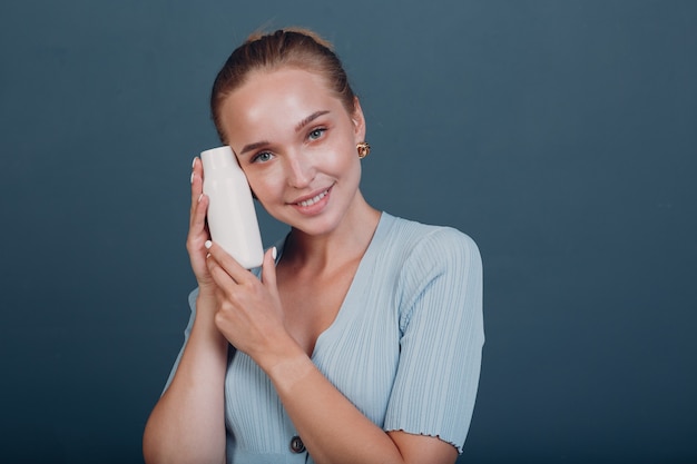 Pretty young woman hold white bottle template blank empty\
space. shampoo or cosmetics