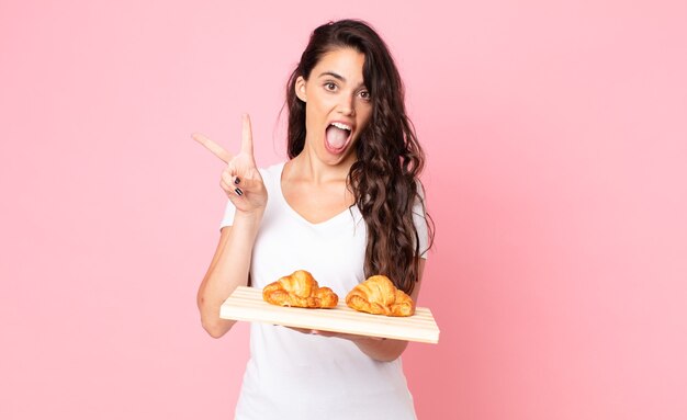 Pretty young woman holding a croissant tray