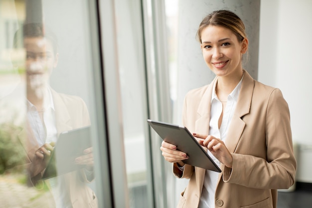 現代のオフィスでデジタルタブレットを保持しているかなり若い女性