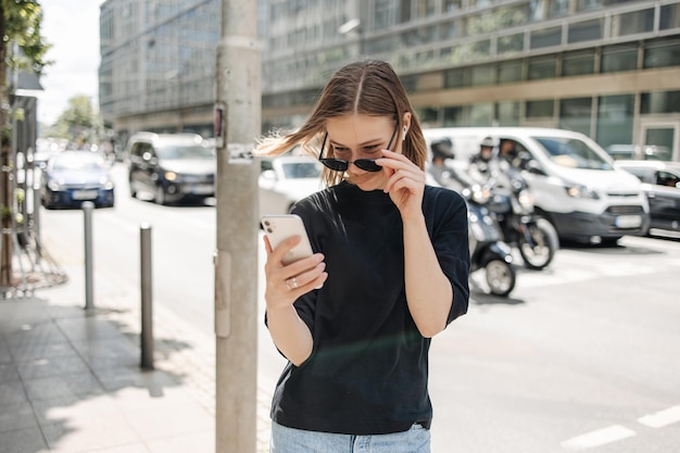 Pretty young woman holding phone in the city