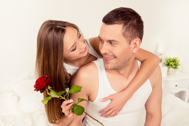 Pretty young woman holding rose and huging her boyfriend