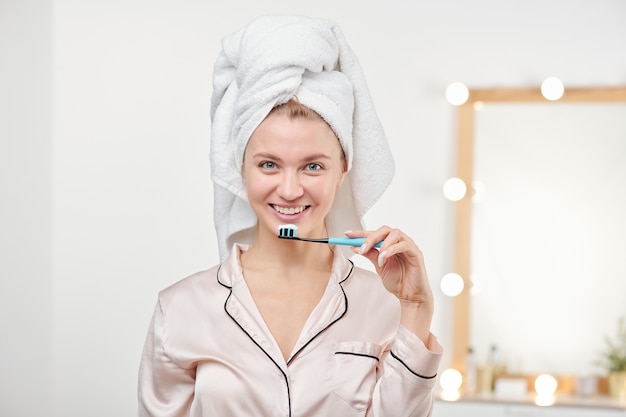 Pretty young woman holding toothbrush by her mouth