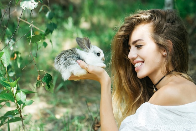 Pretty young woman holds rabbit